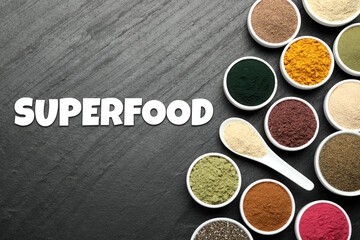 Superfood. Different powders in bowls and spoon on black table, flat lay