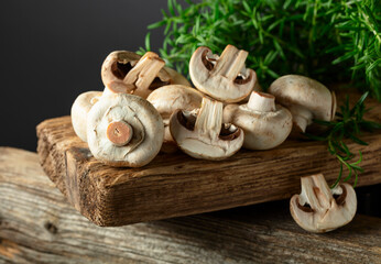 White champignons with rosemary on a wooden board.