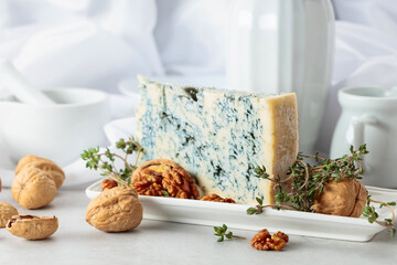 Gorgonzola cheese with walnuts, and thyme on a white table.