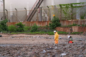 Environmental field team in protective gear analyzes water samples on a polluted beach. One holds a...