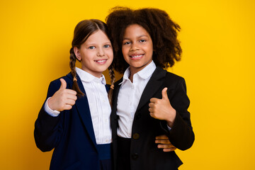 Diverse young friends in professional attire smiling together holding thumbs up on vibrant yellow background