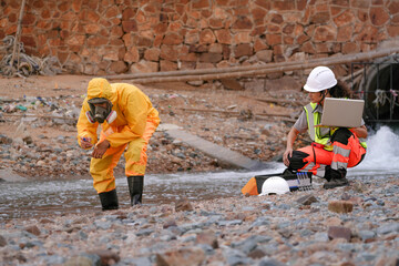 Environmental field team in protective gear analyzes water samples on a polluted beach. One holds a...