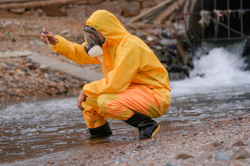 Environmental field team in protective gear analyzes water samples on a polluted beach. One holds a...