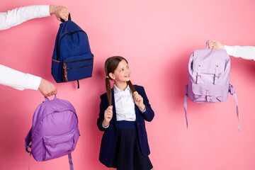 Happy student in school uniform surrounded by colorful backpacks on a pink background, representing...