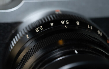 Close up of digital camera manual focus lens with aperture and distance settings.