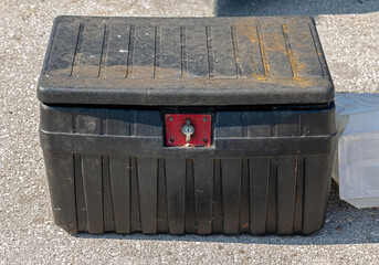 Dirty dusty closed locked black plastic toolbox outside