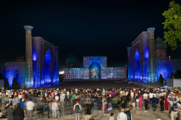 Long exposure of madrasahs at Registan Square with blurred people watch sound and light show in Samarkand, Uzbekistan