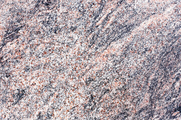 Granite surface close up. Pink gray granite background. Natural stone texture. Rough patterned mineral. Solid rock detail for construction. Decorative building material with hard crystal structure.