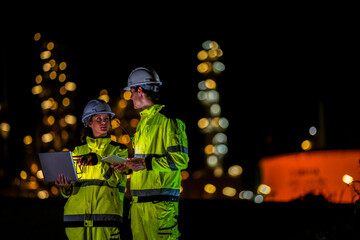 Naklejka premium Two engineers collaborate on a night shift using a laptop and tablet at a plant A concept for the Fourth Industrial Revolution predictive maintenance and the Industrial Internet of Things