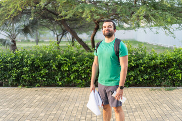 Sportsman holding towel and bottle smiling in park after workout