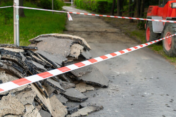 Road construction with red bulldozer and broken asphalt on blocked path