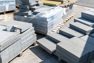 Gray concrete paving slabs stacked on wooden pallets outdoors