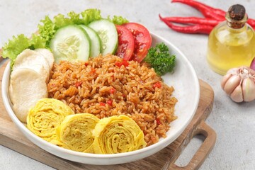 Nasi Goreng. Fried rice served with tomatoes, cucumber and omelet