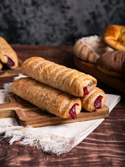 Close-up of three flaky, jam-filled pastries stacked on a wooden board.