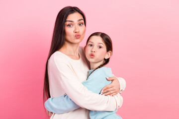 Joyful moment of mother and daughter bonding together, striking a playful pose against a cheerful...