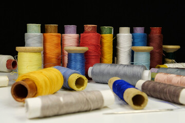 Spools with multi-colored threads on black background, close-up shot