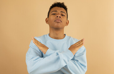 Brown skinned Latino teenager wearing a pastel blue sweatshirt, with an angry face with his hands...