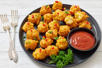 corn nuggets on a plate with tomato sauce