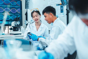 Two young scientists in lab coats and gloves discussing research results in laboratory....