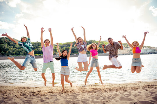 Group of young diverse friends enjoying a fun outdoor beach day together under the sunny sky