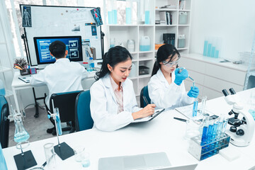 Fototapeta premium Two female scientists analyzing test tube samples in a laboratory setting. One supervises while the other conducts an experiment. Concept of science education, teamwork, and research collaboration.
