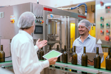 Obraz premium Two professionals discussing wine bottling process inside a modern winery facility in the afternoon