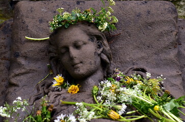Mit Blumen geschmückte Steinfrau auf dem alten Friedhof in Freiburg