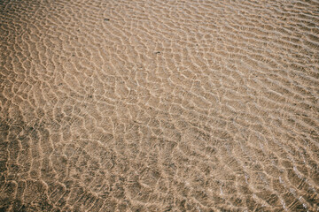 Obraz premium A sandy beach with ripples in the water