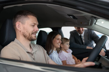 Happy family inside new car and salesman, selective focus