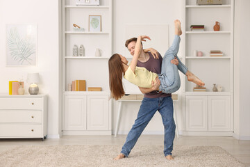 Young couple dancing together at home. Space for text