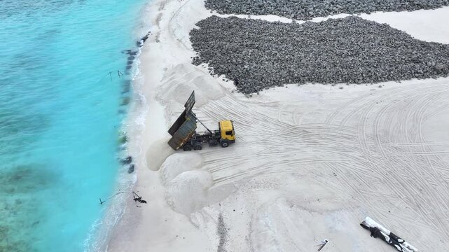 Aerial view of truck unloading sand on reclaimed land, Maldives.