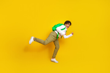 Cheerful young student running excitedly with backpack against bright yellow background symbolizing back to school season