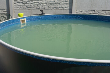 Above ground backyard swimming pool with murky water, concept of home improvement, outdoor...