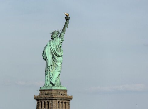 statue isolated against a pale blue sky (iconic icon of freedom prosperity immigration arrivals) lady with torch and crown new york city harbor usa america of french gift new jersey - Powered by Adobe