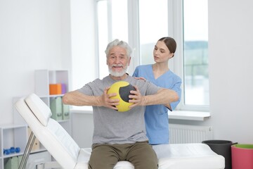 Obraz premium Doctor and patient exercising with medicine ball in clinic