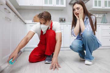 Worried woman and pest control worker spraying insecticide at home