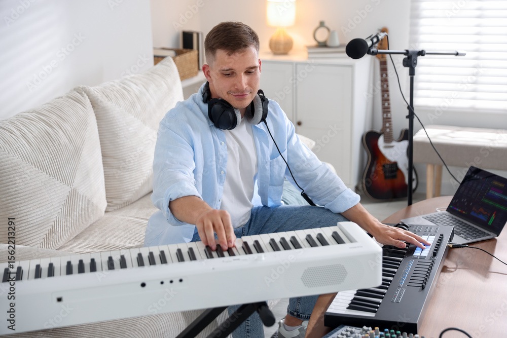 Poster man working with digital piano and midi keyboard in home studio