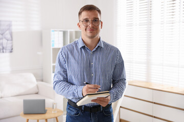 Portrait of psychologist in glasses with notepad and pen in office