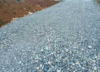 Gravel road surface with small stones and pebbles, leading through a natural landscape, showcasing...