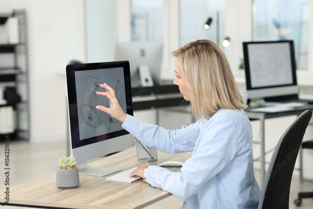 Poster technician making digital engineering drawing on computer at desk in office