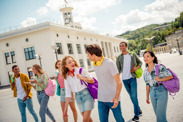Group of young friends enjoying outdoor school trip bonding in a city center on a bright sunny summer day