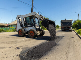 A re -control loader drops asphalt on the side of the road