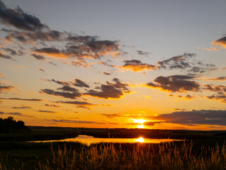 A sunset over a lake with tall grass in the foreground