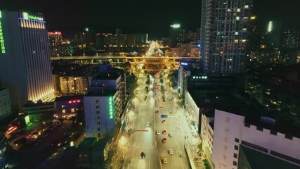 Aerial view of cityscape at night with illuminated skyscrapers and traffic lights.