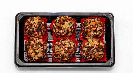 Chocolate dessert balls rolled in hazelnuts in box isolated on white background