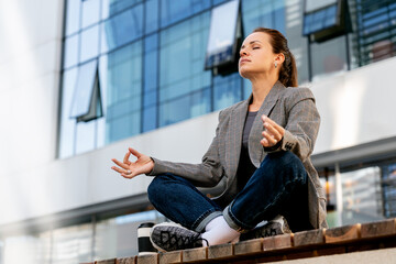 Modern urban office worker meditating during lunch break in downtown. Employee wellbeing.