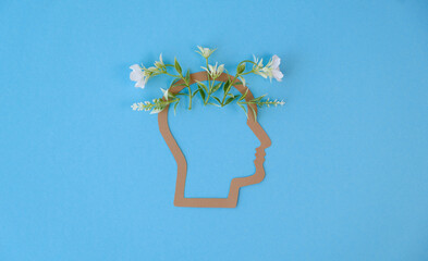 A head with flowers on it. The head is on a blue background, Mental Health Concept