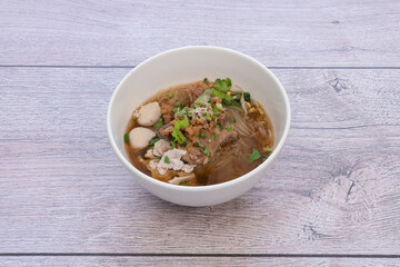 bowl of noodles with vegetables on wooden table.