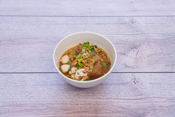 bowl of noodles with vegetables on wooden table.
