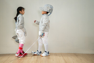 Before the tournament day, a boy and girl dressed in fencing gear are rehearsing in gym